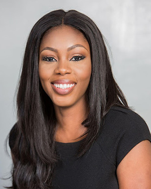 A young woman smiling, in a black dress with a white background.